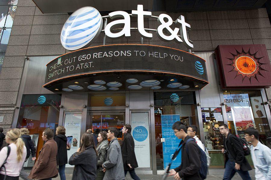 People walk by an AT&T retail store, Monday, Oct. 24, 2016, in New York. AT&T plans to buy Time Warner for $85.4 billion. (AP Photo/Mark Lennihan)