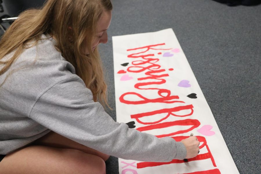 Julia Mickelson works on the yearbook sign for the upcoming event. 