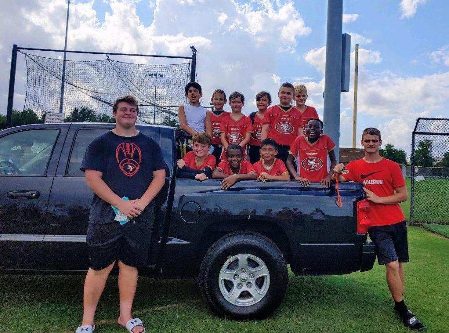 Proudly posing with junior Max Roberts new truck, junior Nolan Steeples , the 49er Farm League  football team, and Roberts take time after a game to celebrate Roberts coaching skills. The parents gifted Roberts the truck for his dedication to their children.