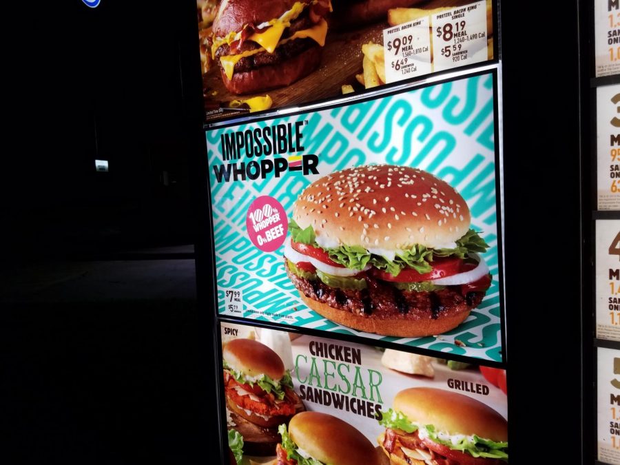 Burger Kings outside menu boasts a large section showcasing the new Impossible Whopper alongside its traditional meat-based burgers. 