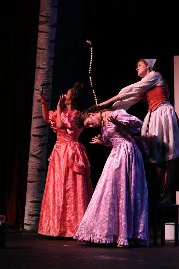 Cinderella, played by senior Abigail Reed, yanks the hair of her step-sisters, played by senior Lily Tungol.