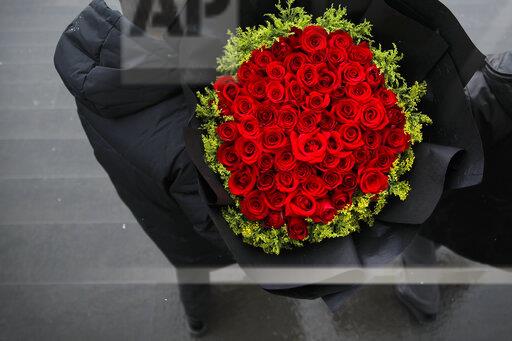 A bouquet of roses is exchanged in a Beijing market between seller and customer on Valentine's Day. The holiday, popular in Western culture, has recently boomed in China with encouragement from various vendors. This indicated that in the future, Valentine's Day might become a worldwide celebration of love.