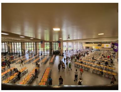 Students search through tables with for an open spot without a brightly colored X to sit in the commons.