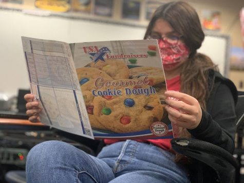 Senior Natalia Bond browses through the Cookie Dough Fundraiser product brochures in a classroom. Seniors are encouraged but not required to participate in the money-making event for prom.