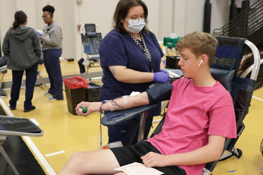Blood donor, Senior Ben Riddle, squeezes a ball to help the blood flow while donating at the annual Klein Oak HOSA drive. 