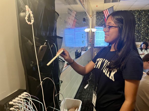 Placing her phone into the cell phone storage pouch, sophomore Alina Moman earns LiveSchool points in Humanities teacher Danielle Campos's class.