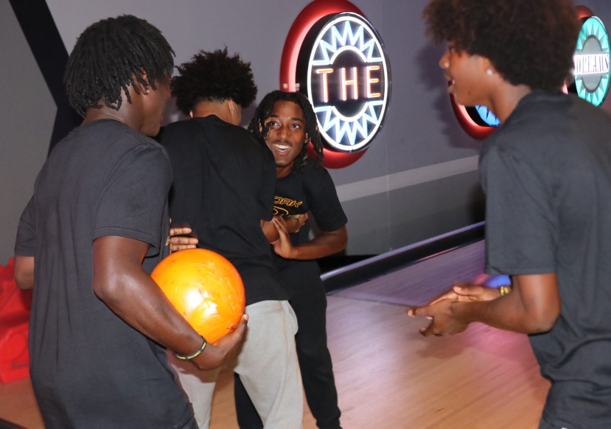 Juniors Raiden Ross and Jalyn Black hupe up their teammates senior Desmond Sheffield and sophomore King Greathouse as they get ready for their turns. The varsity team bowled and ate pizza together Aug. 22 at Bowlero to build bonds that could carry them through the season ahead.